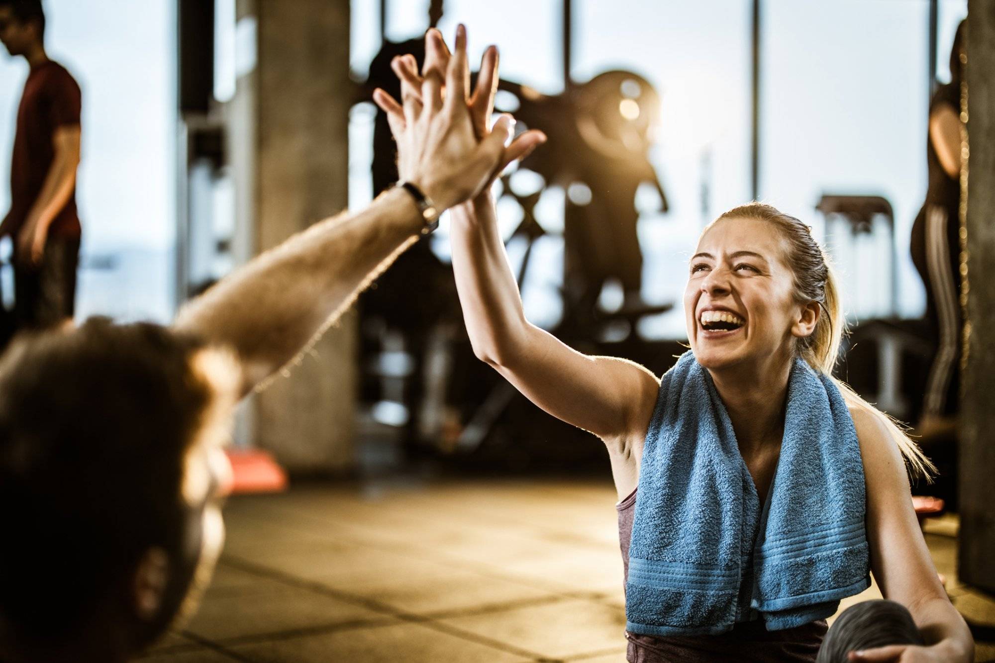 Happy athletic woman giving high-five to her friend on a break in a gym.