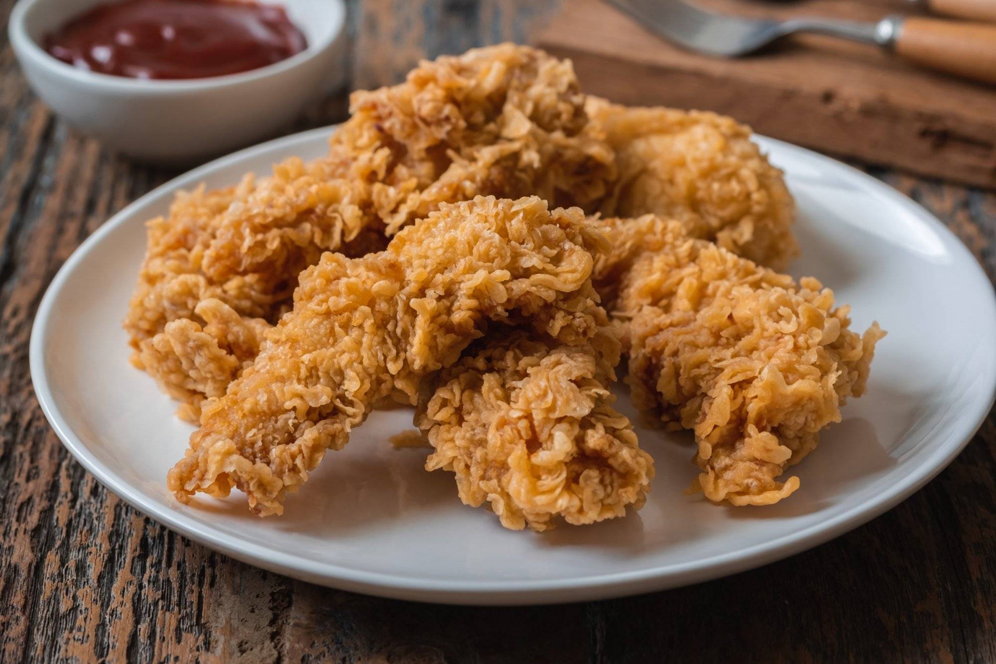 Crispy fried breaded chicken strips on plate and ketchup